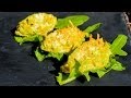 Drei gefüllte Zucchiniblüten auf einem Blatt Rucola, frisch zubereitet und angerichtet.